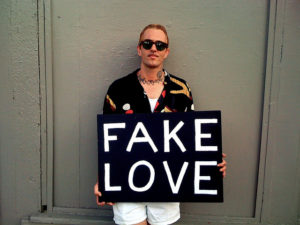 guy holding "fake love" sign