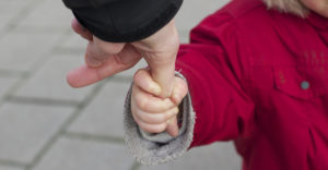 young child holding adult finger--Coparenting with a narcissist